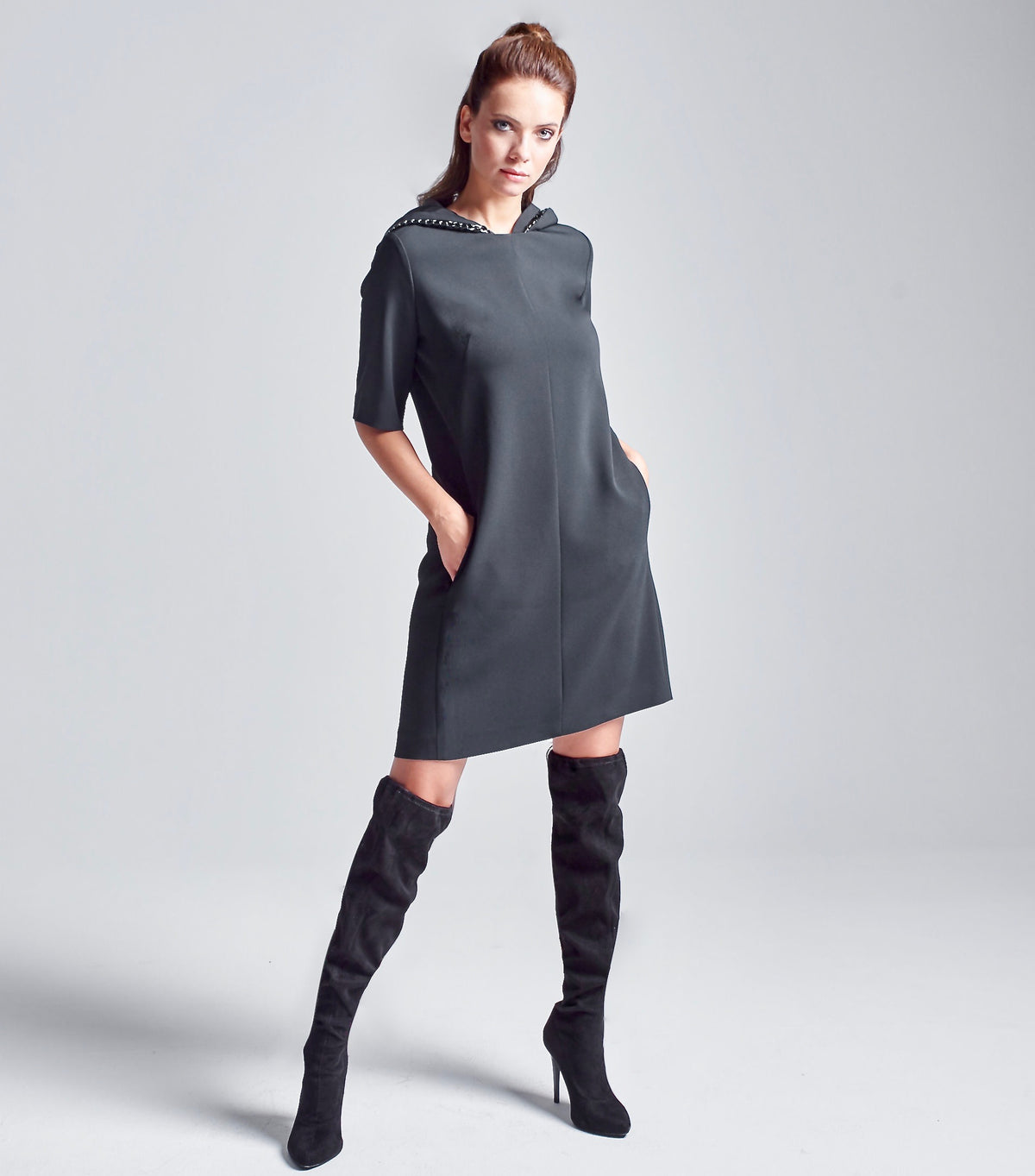 Das Model trägt den abnehmbaren Kapuzenkragen auf dem Multiplyfashion Shift-Kleid. Die Kapuze fällt auf diesem Bild leger über die Schultern.