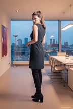 Das Model trägt ein schwarzes, ärmelloses Multiplyfashion Etuikleid im eleganten Büro in München.