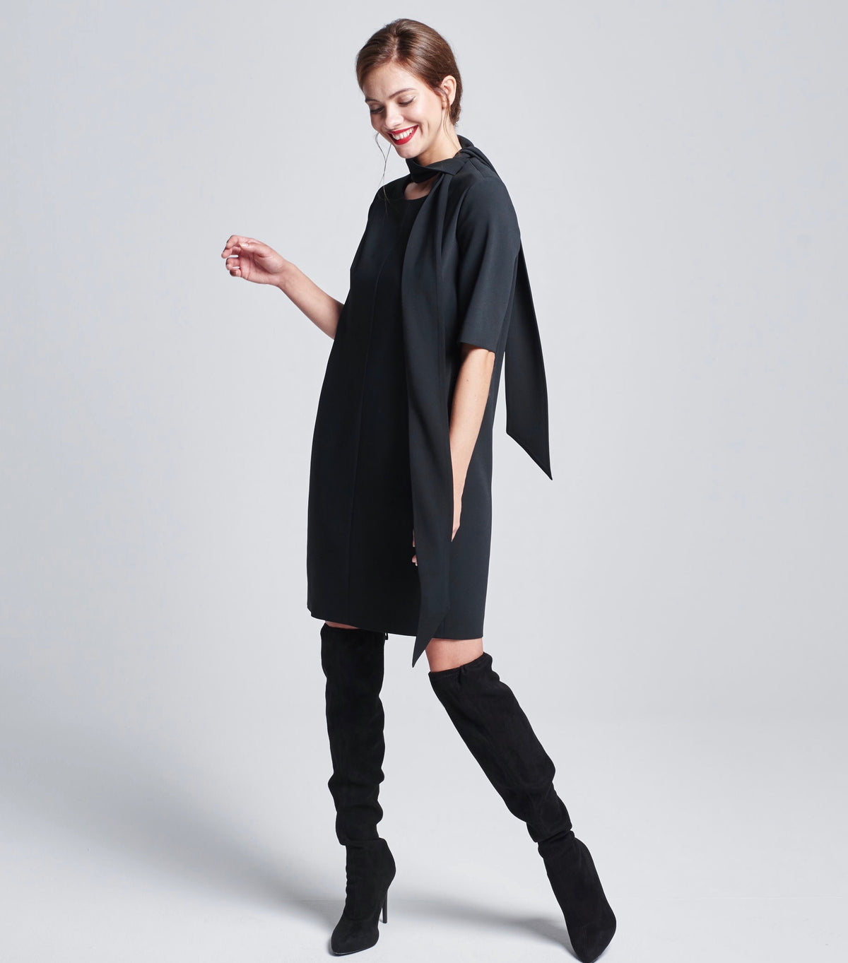 Das Model trägt den schwarzen Multiplyfashion Schalkragen chic zur Seite geknotet auf dem schwarzen Multiplyfashion Shiftkleid.