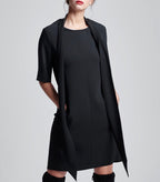 Das Model trägt den schwarzen Multiplyfashion Schalkragen leger offen auf dem schwarzen Multiplyfashion Shiftkleid.