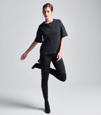 Schwarzes Multiplyfashion Shift Oberteil kombiniert mit der eng anliegenden Multiplyfashion Hose und Overknee-Stiefeln. 
